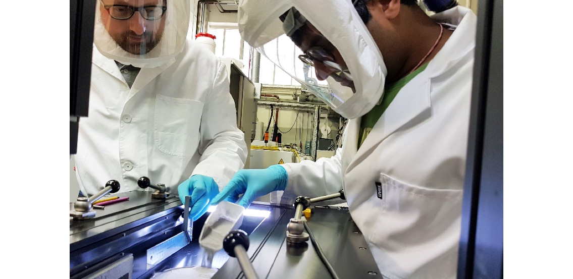 Bild von zwei Mitarbeitenden bei der Arbeit an einer Laser-Pulverbettschmelzanlage